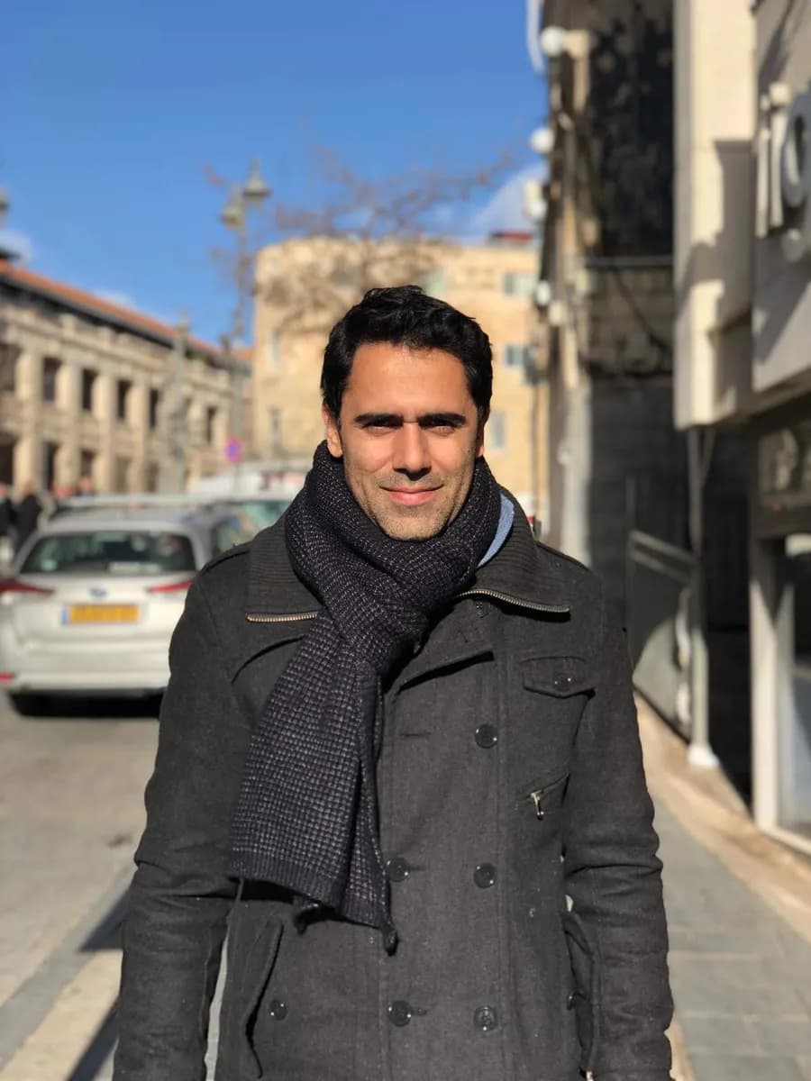 Sinay in a winter coat and scarf on a sunny city street